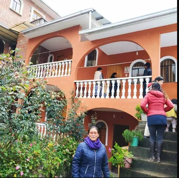 A woman standing on the steps of an orange building.