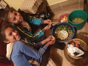 Two people sitting in front of a bowl of food in bolivia